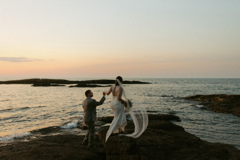 Couple walking along Presque Isle at sunset holding hands in Marquette, Michigan.