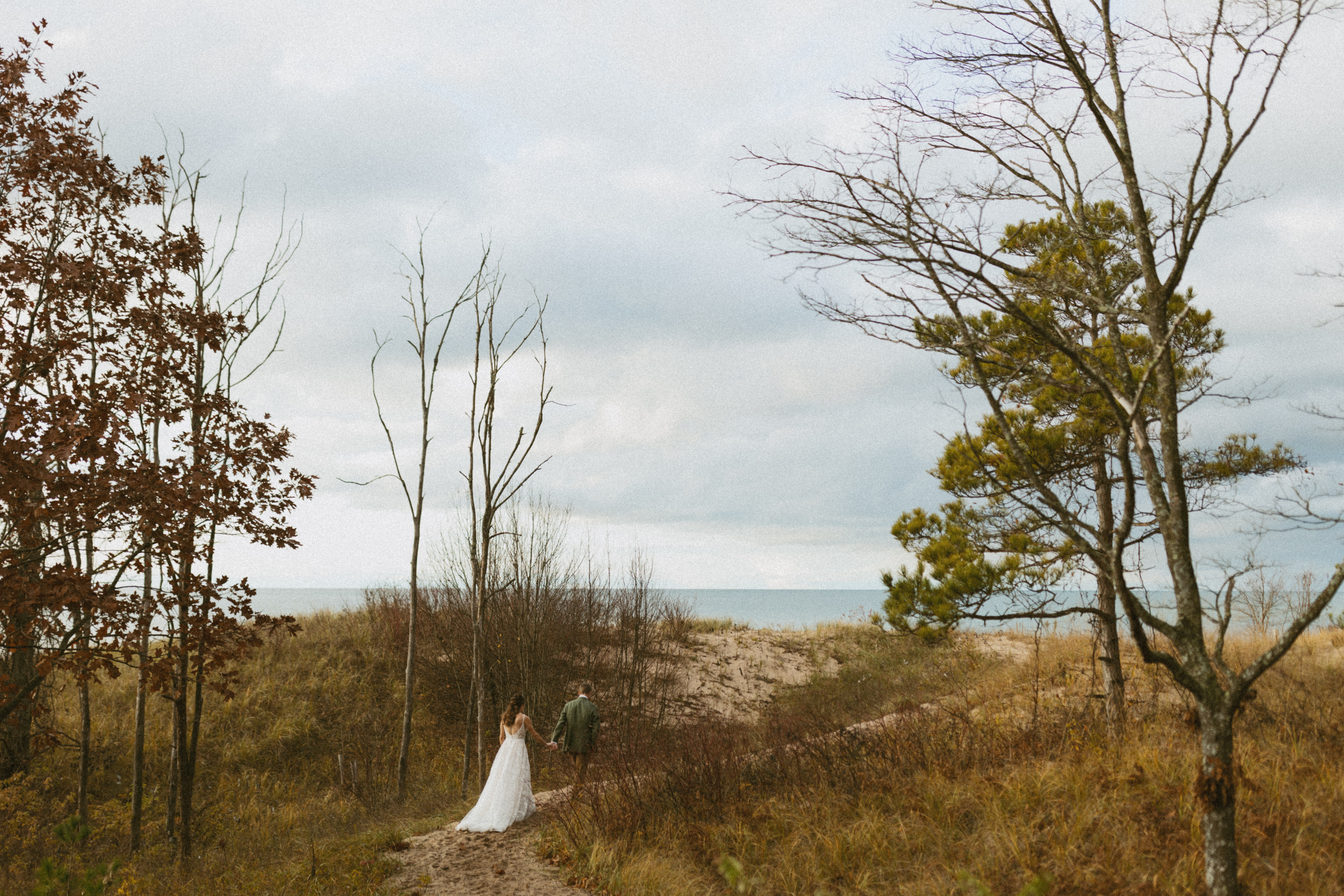 Bride and groom walking along sleeping bear dunes beach during their fall elopement