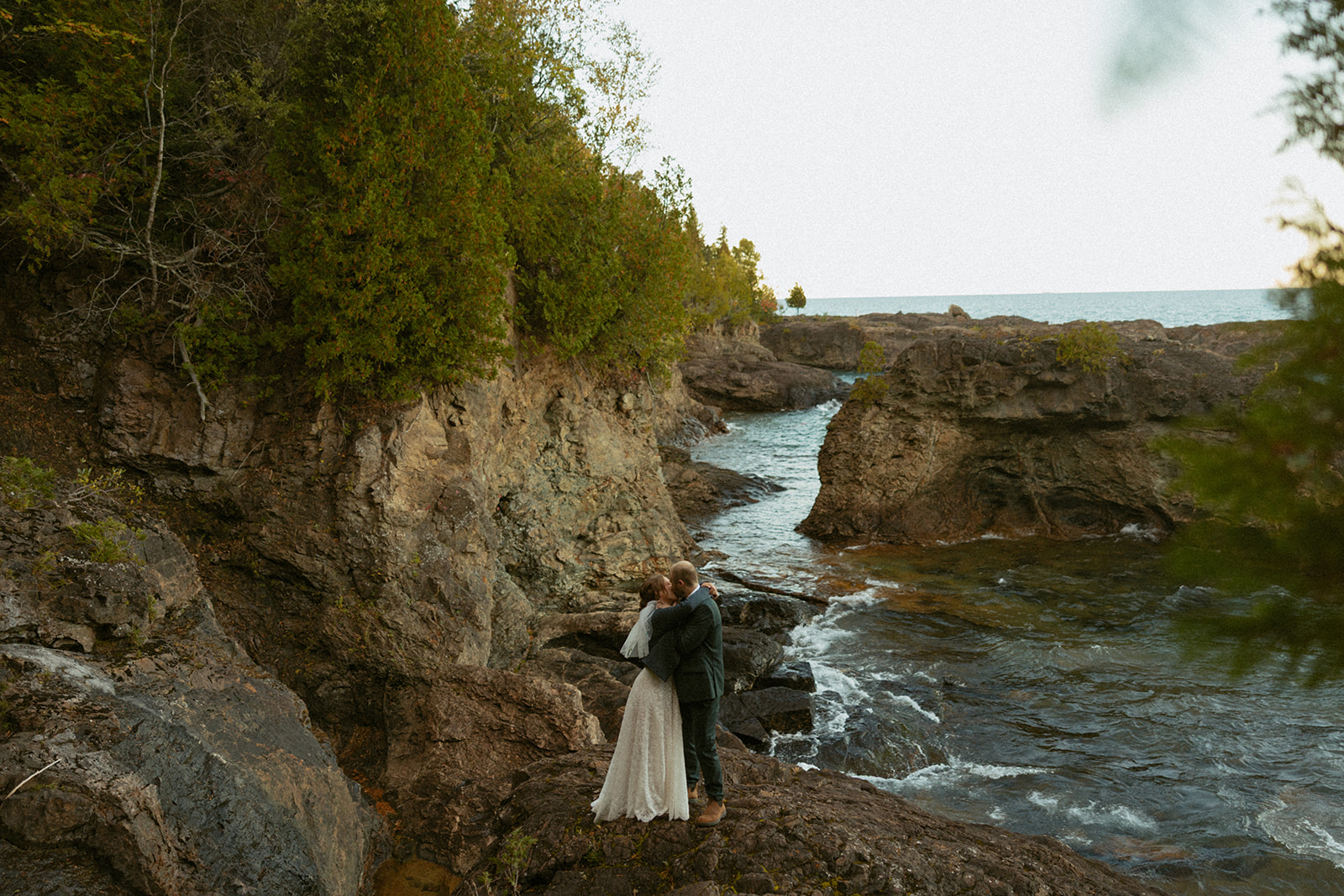 Couple on their wedding day in front of cliffs and water and trees in Michigan's Upper Peninsula