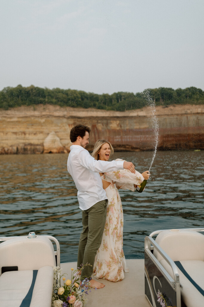 Eloping couple spraying champagne at Pictured Rocks National Lakeshore on a boat